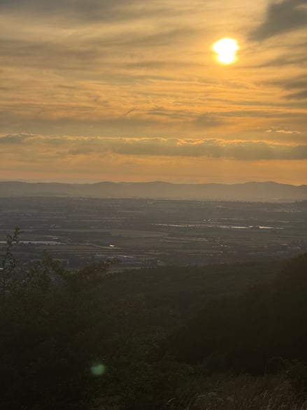 The sun setting over the rolling hills in the distance.