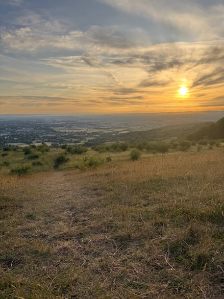 the sun is high in the background, lighting up the walking trail at Cleeve Hill.