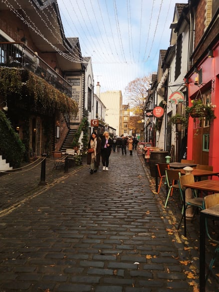 Cobbled street with bars, restaurants, and outdoor seating in Glasgow
