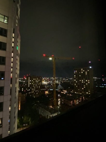 View of Leeds city skyline at night with illuminated buildings and construction crane