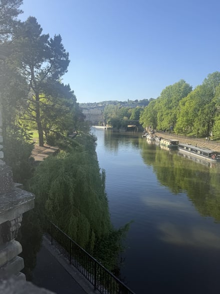 Calm river scene with greenery and reflections along the riverside path
