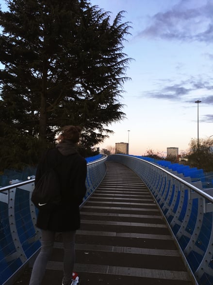 Pedestrian bridge with city skyline views at dusk