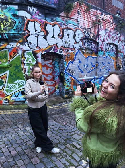 Students filming in front of colourful graffiti wall in Bristol