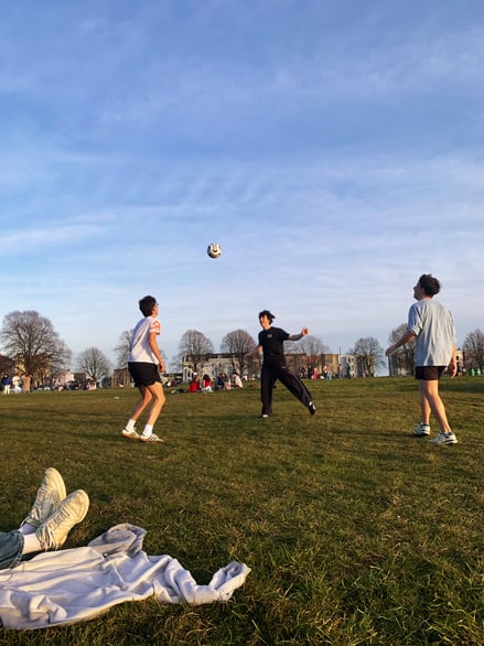 Friends playing football on grass in Bristol park