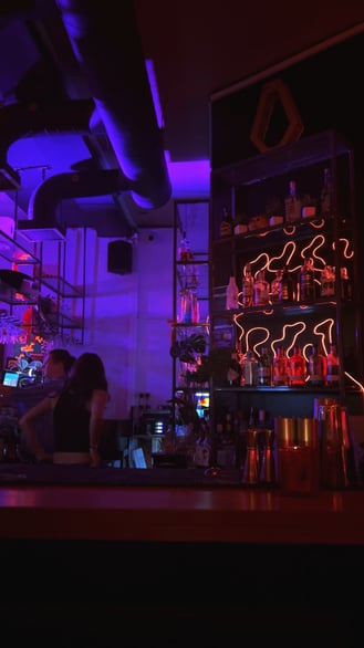 Bar interior with neon lighting and drinks displayed on shelves