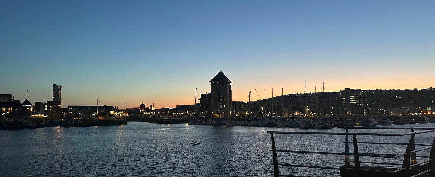 Waterfront view at dusk with buildings and reflections on the water