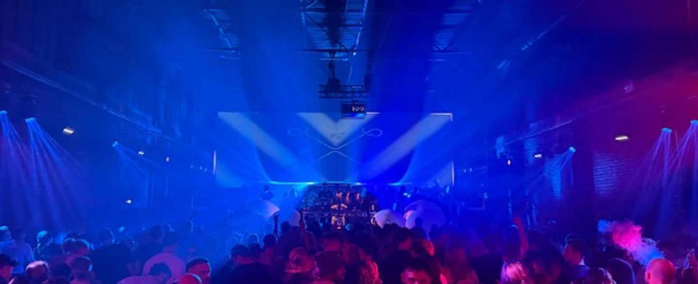 Large crowd dancing in a nightclub with blue and red lighting in Leeds