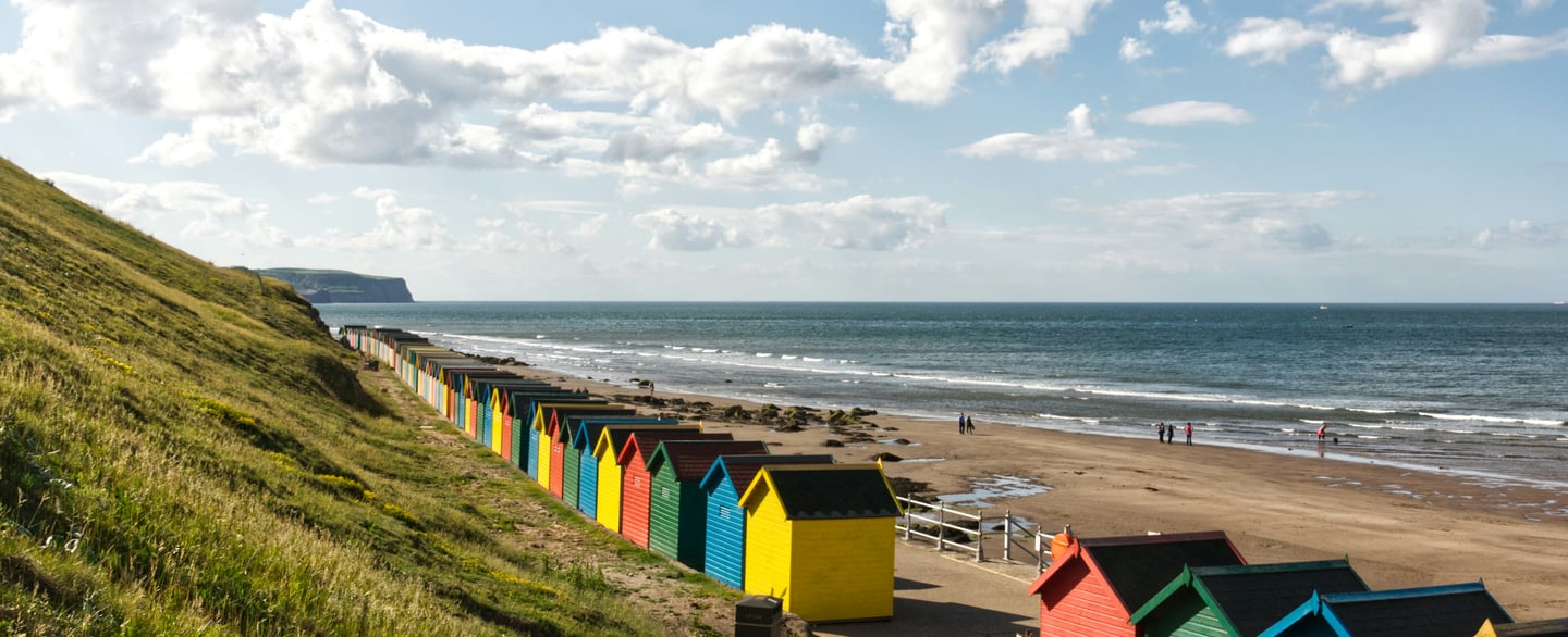 An image of beach huts along the beach in Brighton