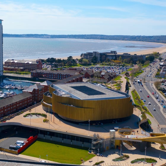Student with phone in front of Swansea landmarks