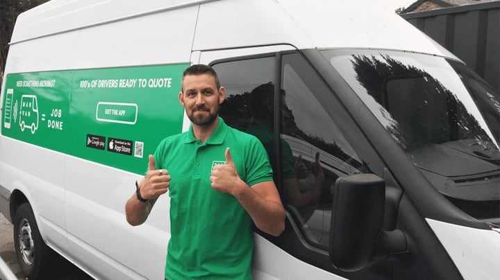 A Man and Van driver is stood next to his van giving thumbs up to the camera